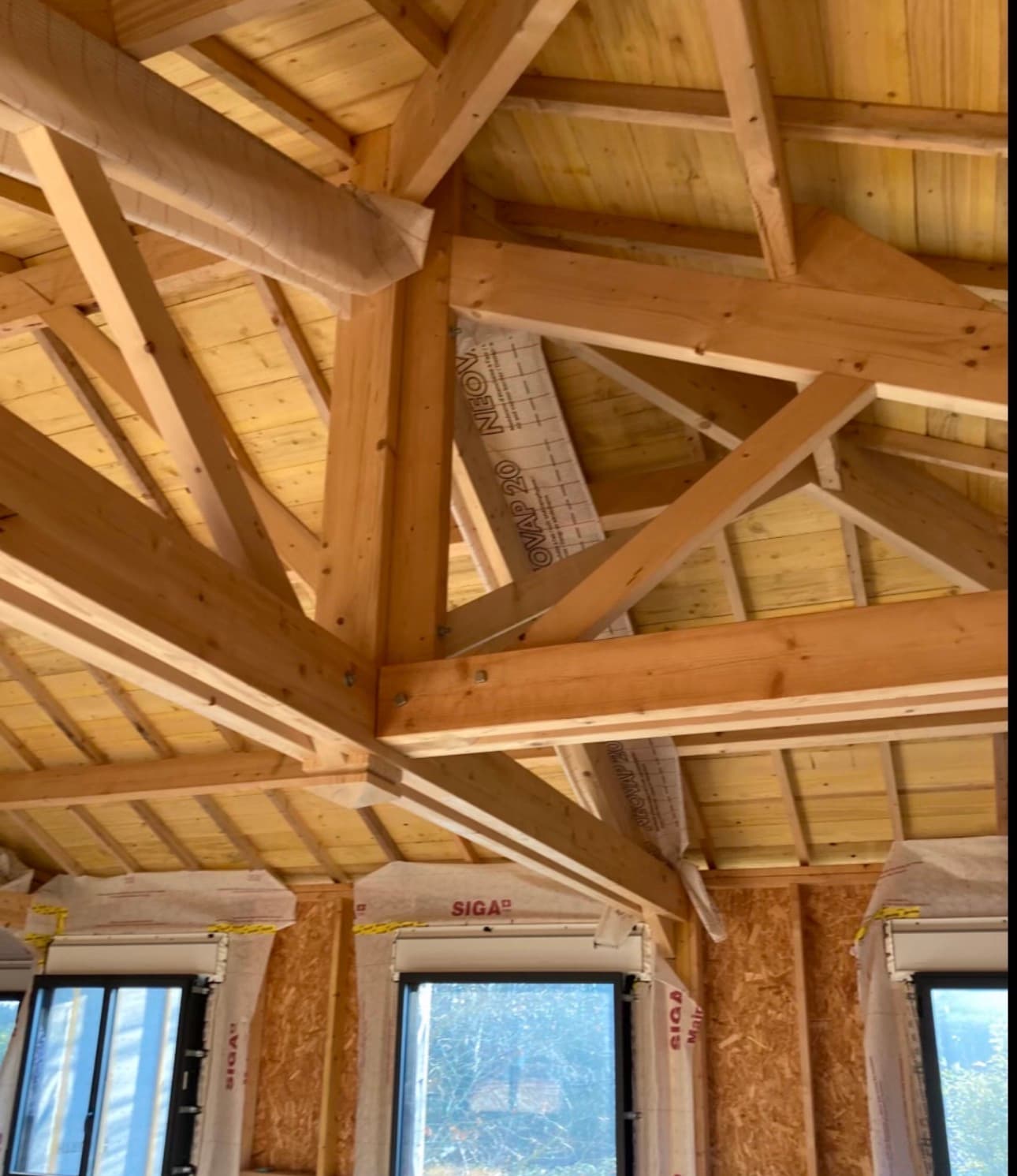 Charpente en bois apparente avec poutres massives à l'intérieur d'une maison en cours de construction.